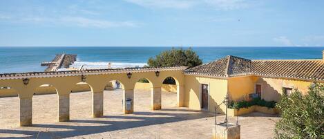 A coastal building with a tiled roof and arches, overlooking the sea.