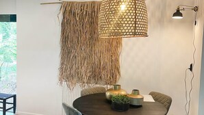 Een eethoek met een ronde tafel, stoelen en een hanglamp.