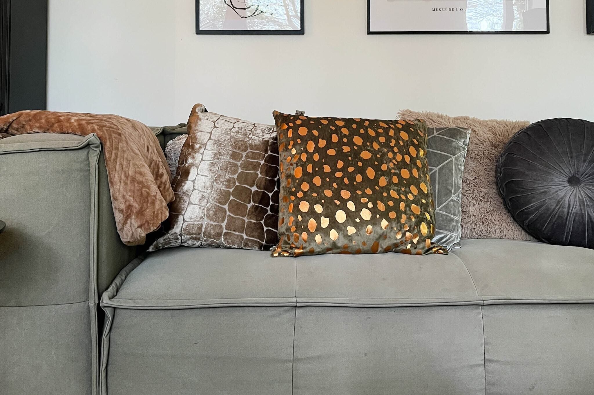 A grey sofa with various patterned cushions.