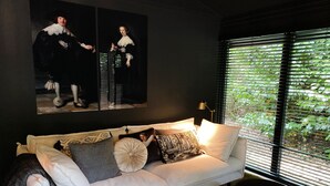 Ein modernes Wohnzimmer mit einem weißen Sofa, dekorativen Kissen und einem Gemälde von zwei Personen.