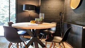 Ein runder Holztisch mit schwarzen Stühlen, einer schwarzen Lampe und einer Glasvase mit Pflanzen.