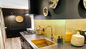 Una cocina moderna con un lavamanos de acero inoxidable, una estufa a gas y un salpicadero negro.