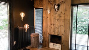 Una habitación con pared de madera, una chimenea y dos lámparas.
