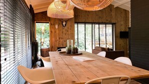 Una mesa de comedor de madera con sillas, un centro de mesa con superficie de vidrio y un televisor montado en la pared.