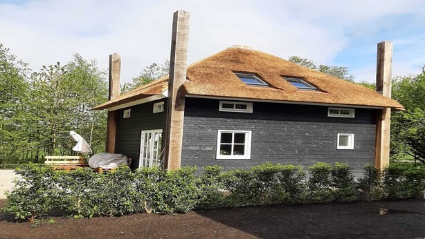 Ein kleines, dunkel gefärbtes Haus mit einem Strohdach, zwei Fenstern und einem Schornstein.