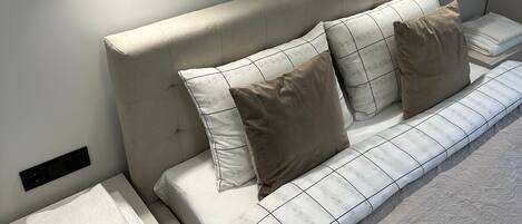 A modern bedroom with a bed, two bedside tables, a nightstand, and two wall-mounted lights.