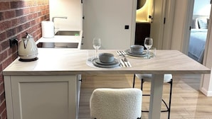A modern kitchen with a central island, white cabinetry, and a brick accent wall.