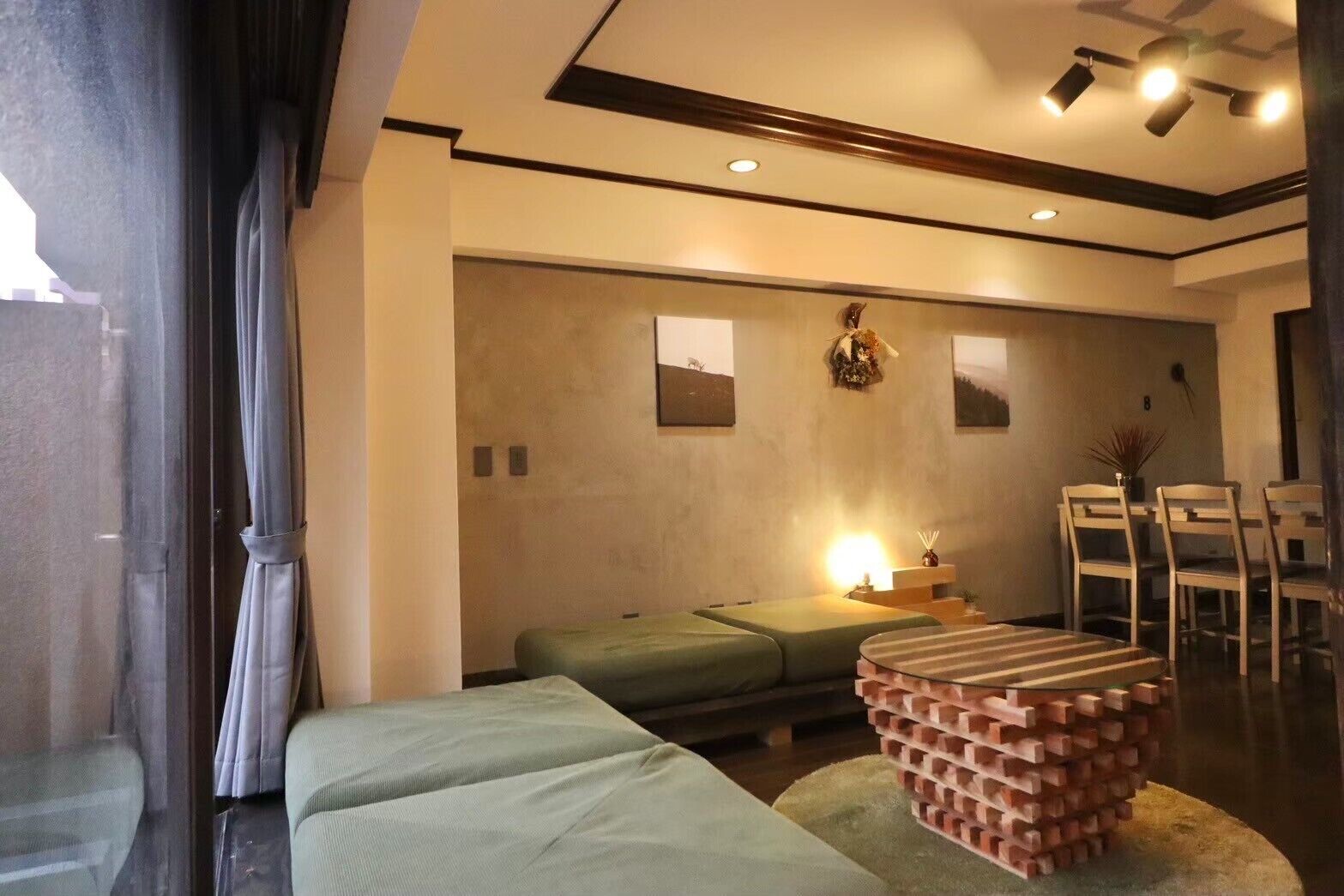 A modern room with a sofa, a small table, and a dining area with chairs.