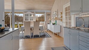 A modern kitchen with a large island, white cabinetry, and a view of the outdoors.