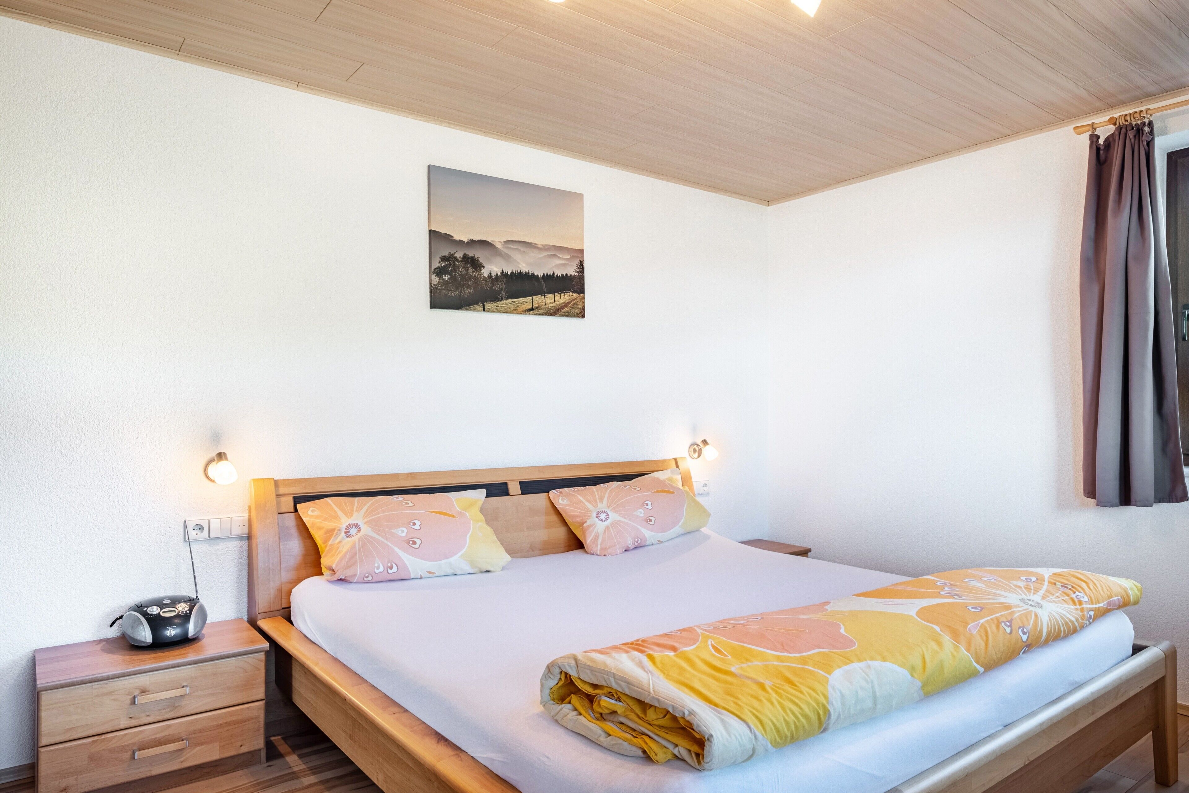 Une chambre à coucher avec un lit, une table de chevet, une lampe et un tableau au mur.