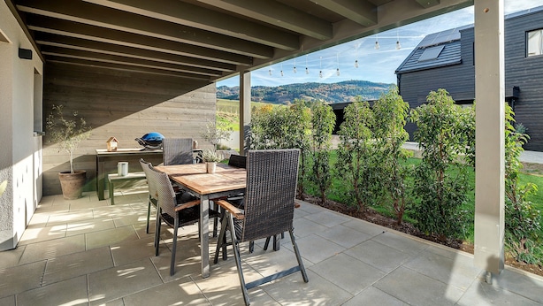An outdoor patio with a table and chairs, a pergola overhead, and a view of a house and hills in the background. - Cozy Apartment in Oberkirch – Enjoy Nature & Central Location (Oberkirch)