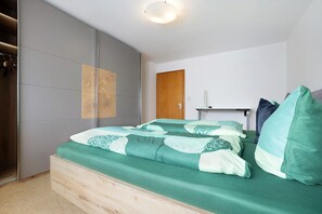 Ein Schlafzimmer mit einem Bett, einem Holzschrank, einer Tür und einem kleinen Tisch.