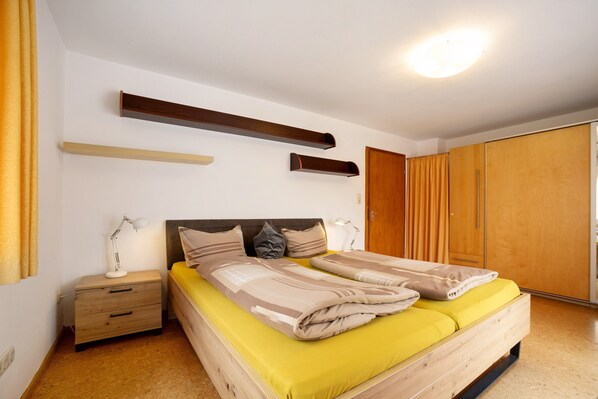A bedroom with a bed, bedside tables, a wardrobe, and a ceiling light. - Holiday Home 'Hilde' with Mountain View, Private Terrace and Wi-Fi (Schwangau)