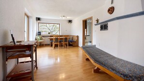 A room with a wooden bench, a dining table with chairs, a window with a view, and a ceiling light fixture. - Holiday Home 'Hilde' with Mountain View, Private Terrace and Wi-Fi (Schwangau)