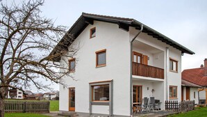 A two-story house with a balcony, a small patio with outdoor furniture, and a fenced yard. - Holiday Home 'Hilde' with Mountain View, Private Terrace and Wi-Fi (Schwangau)
