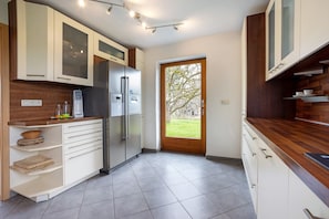 Una cocina moderna con armarios blancos, un refrigerador de acero inoxidable y una encimera de madera.