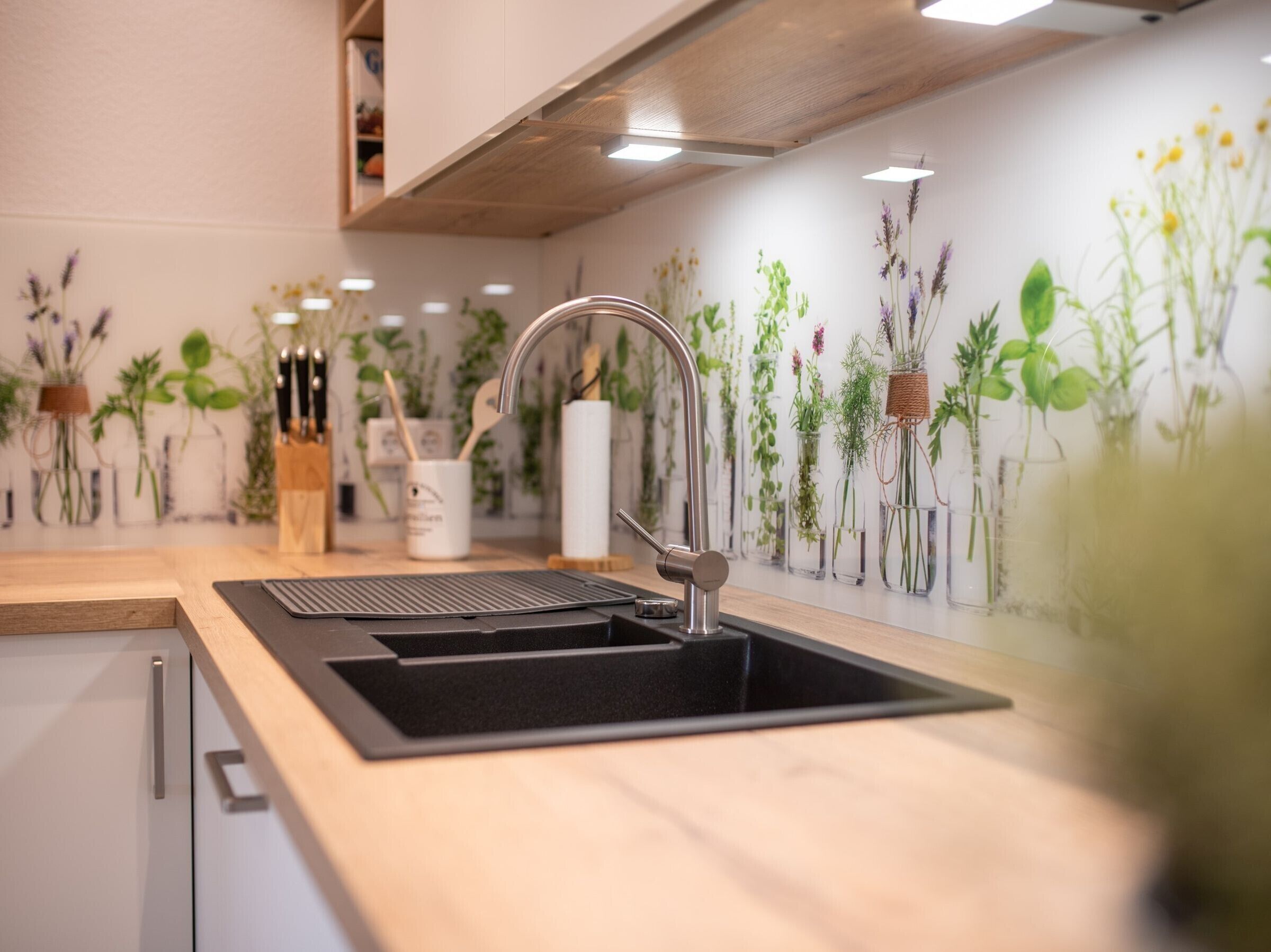 A kitchen with a black sink, stainless steel faucet, and a wooden countertop.