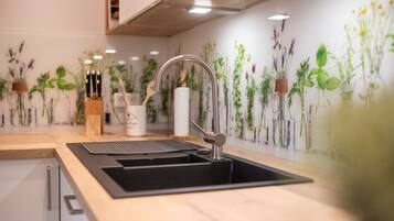 A kitchen with a black sink, stainless steel faucet, and a wooden countertop.