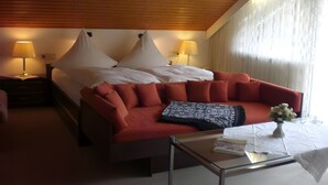 Een hotelkamer met een bed, een rode bank, een glazen salontafel en twee bedlampjes.