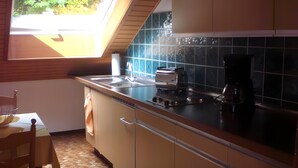 Een keuken met een raam, een spoelbak, een fornuis en een koffiezetapparaat.
