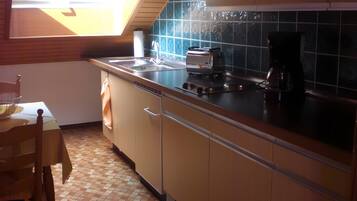 Eine Küche mit Fenster, Spüle, Herd und Kaffeemaschine.