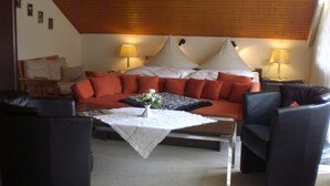 Een woonkamer met een bank, twee fauteuils, een salontafel en een lamp.