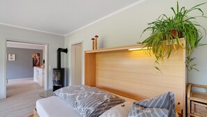 Una camera da letto con un letto, comodini, una pianta fissata al muro e un camino a legna integrato.
