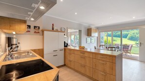 Una cucina moderna con piano cottura integrato, mobili in legno e un'ampia finestra che si affaccia su un giardino.