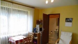 Una habitación con una mesa de comedor, sillas, cafetera, lavabo y ducha.
