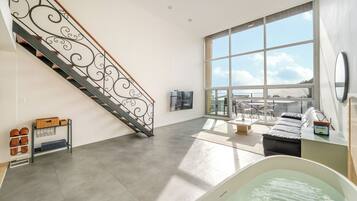 Amplia sala de estar con un ventanal grande, una escalera con barandilla decorativa y una zona de estar con vistas.