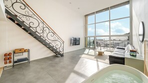 Amplia sala de estar con un ventanal grande, una escalera con barandilla decorativa y una zona de estar con vistas.