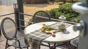 An outdoor table with a plaid tablecloth, a wooden cutting board, a lantern, and yellow tulips.