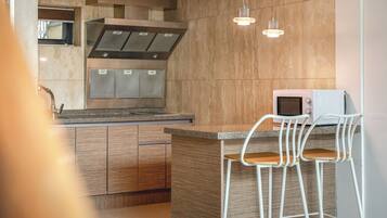 Cocina moderna con una isla central, electrodomésticos de acero inoxidable y un taburete blanco.