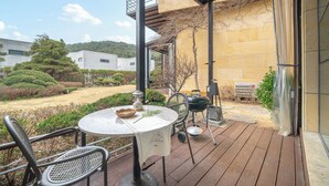 Un patio exterior con una mesa redonda, sillas, una parrilla y una cesta.
