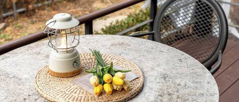 A round table with a woven placemat, a lantern, and a bouquet of yellow flowers.