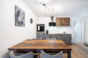 Una cocina moderna con una mesa y sillas de madera, microondas, horno y armarios de madera.