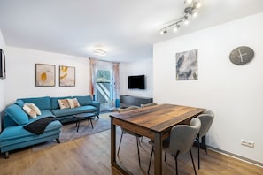Una sala de estar moderna con un sofá, una mesa de comedor de madera y sillas.