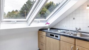 Una cocina moderna con tragaluces, lavavajillas y pileta.