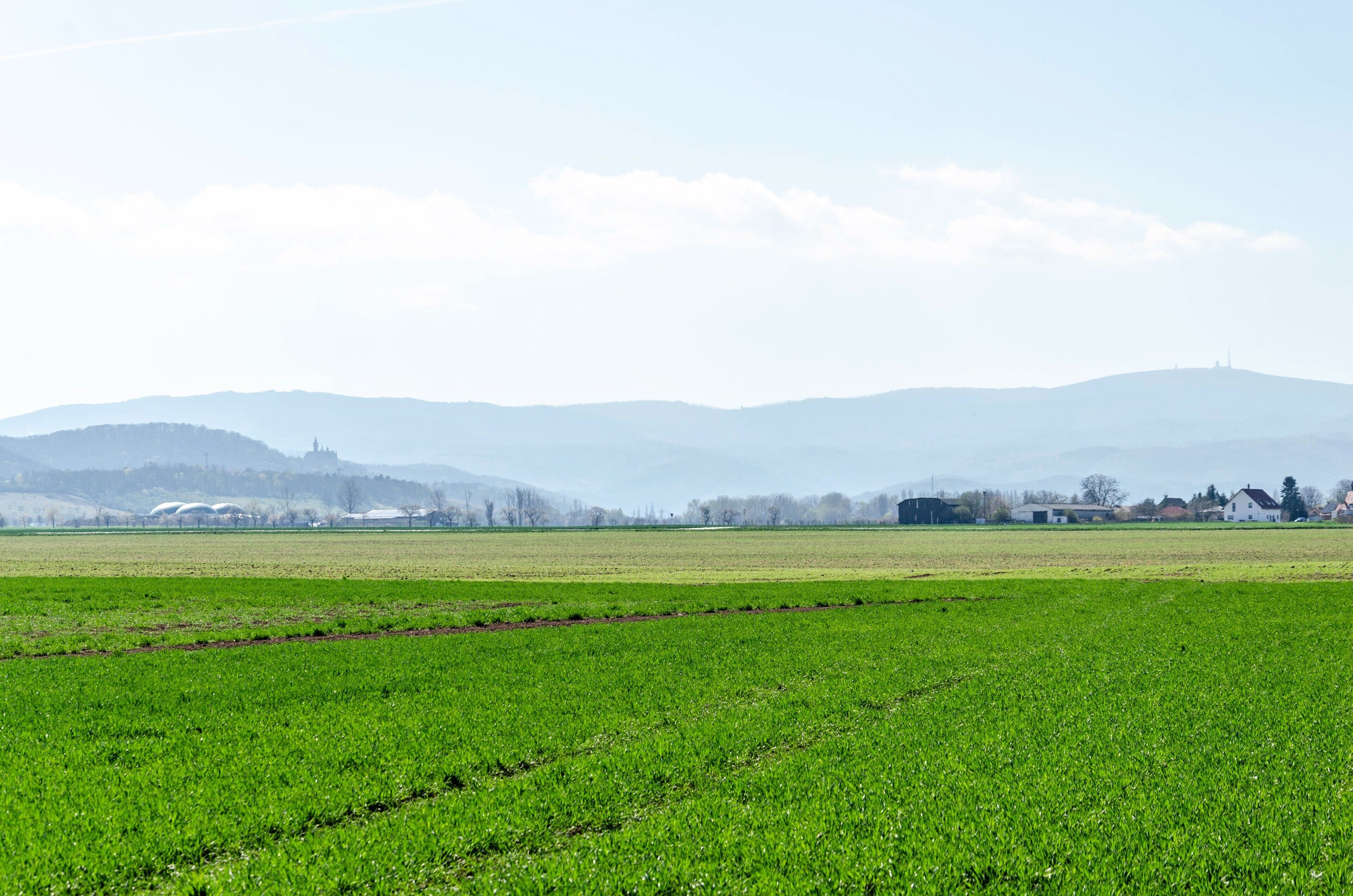 Un paisaje rural con campos, colinas a lo lejos y edificios dispersos.