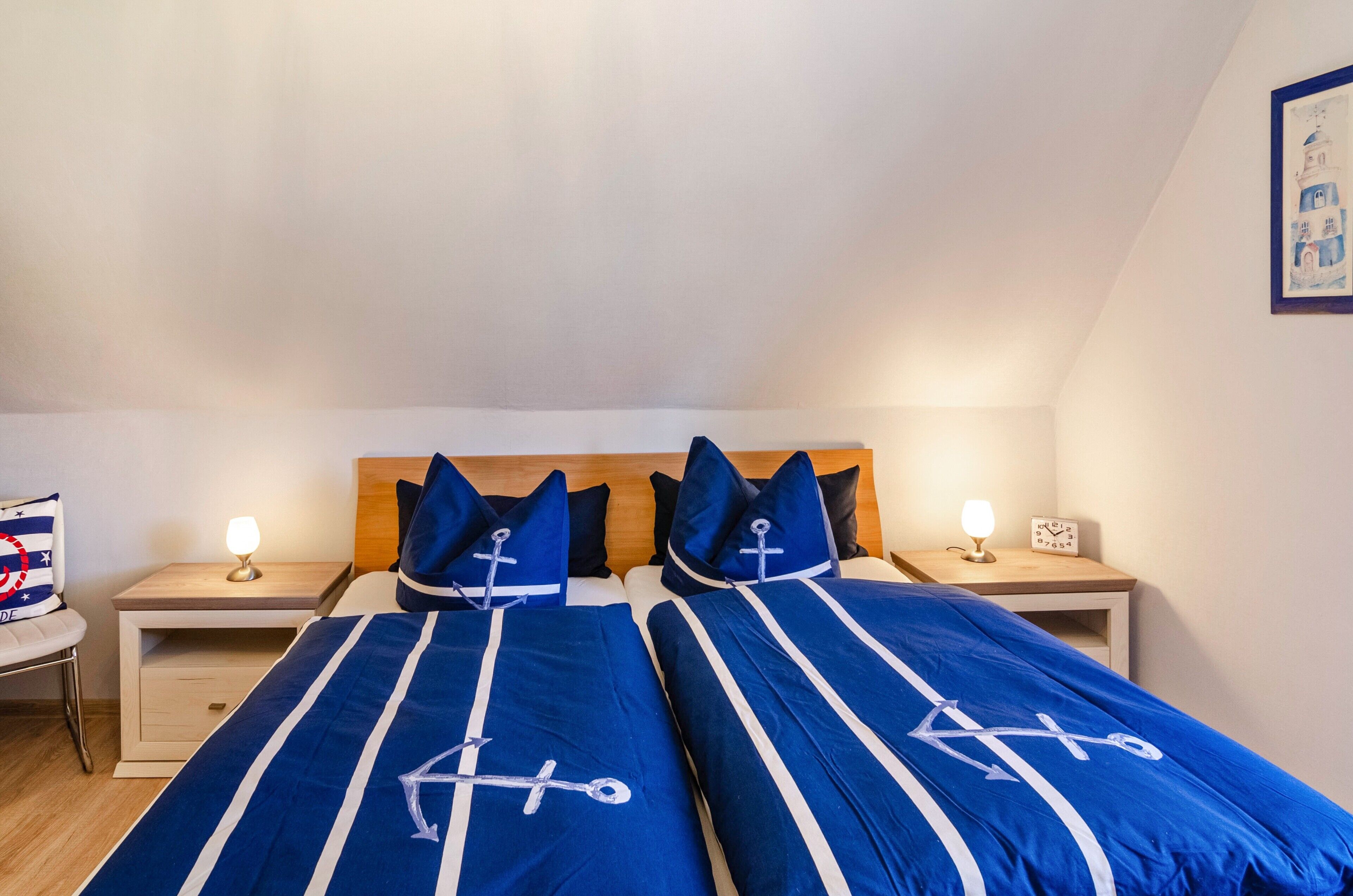 Ein Schlafzimmer mit zwei Betten, Holz-Kopfteilen, Nachttischen mit Lampen und einer Wanduhr.