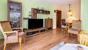 Un soggiorno con TV a schermo piatto, arredamento in legno, una libreria e un'area pranzo.