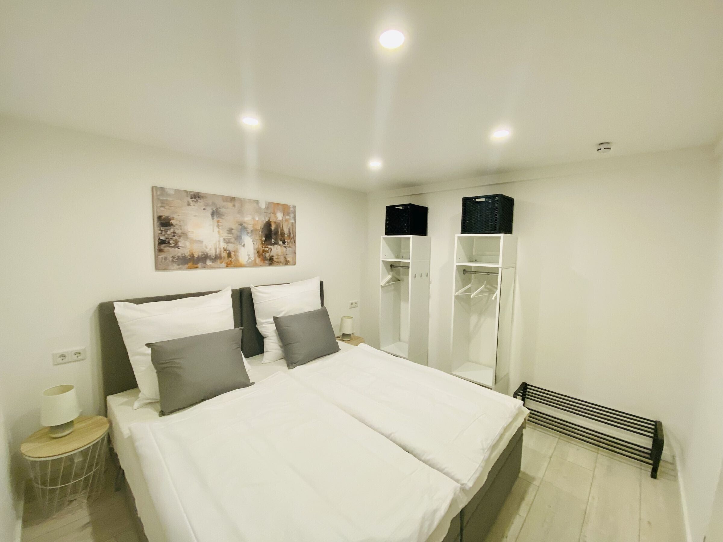 Ein modernes Schlafzimmer mit einem großen Bett, Nachttischen, einem Kleiderschrank und einer Heizung.