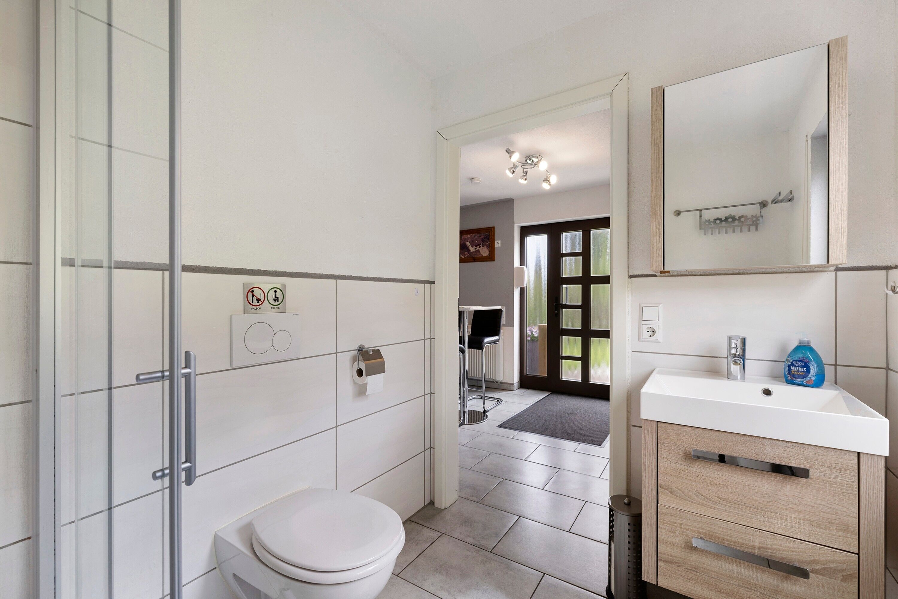 Une salle de bain moderne équipée de toilettes, d’un lavabo et d’une douche à parois en verre.