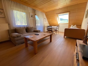 Une pièce chaleureuse avec un plafond en bois, un canapé, une table à manger avec des chaises et un lit.