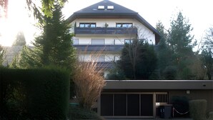 Een gebouw met twee verdiepingen, inclusief een garage, omgeven door groen.