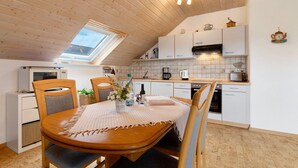 A cozy kitchen with wooden ceiling, a dining table with chairs, and a skylight.