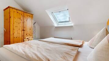 Ein Schlafzimmer mit einem Oberlicht, einem Holzschrank, zwei Betten und einer Heizung.