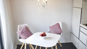 A modern kitchen with white cabinetry, a chandelier, and a table with two chairs and a bowl of fruit. - Studio 'Charmingsuite' with Private Terrace, Shared Garden and Wi-Fi (Bad Teinach-Zavelstein)