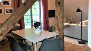 Een eethoek met een tafel, stoelen en een bloevas.