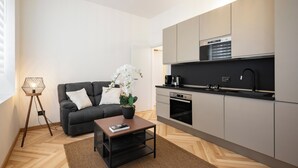 A modern kitchen with grey cabinets, a black countertop, and a built-in oven.